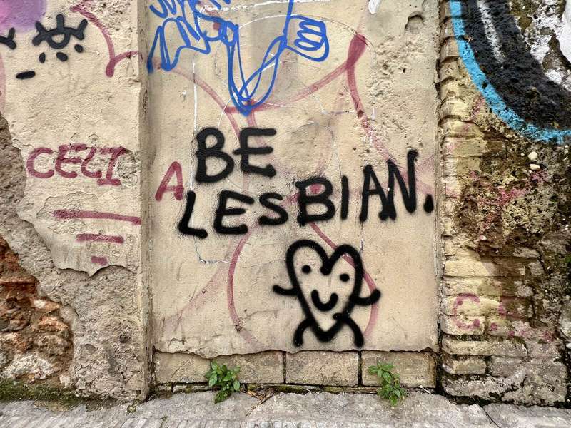 Grafit en una paret: “Be lesbian” i un cor somrient